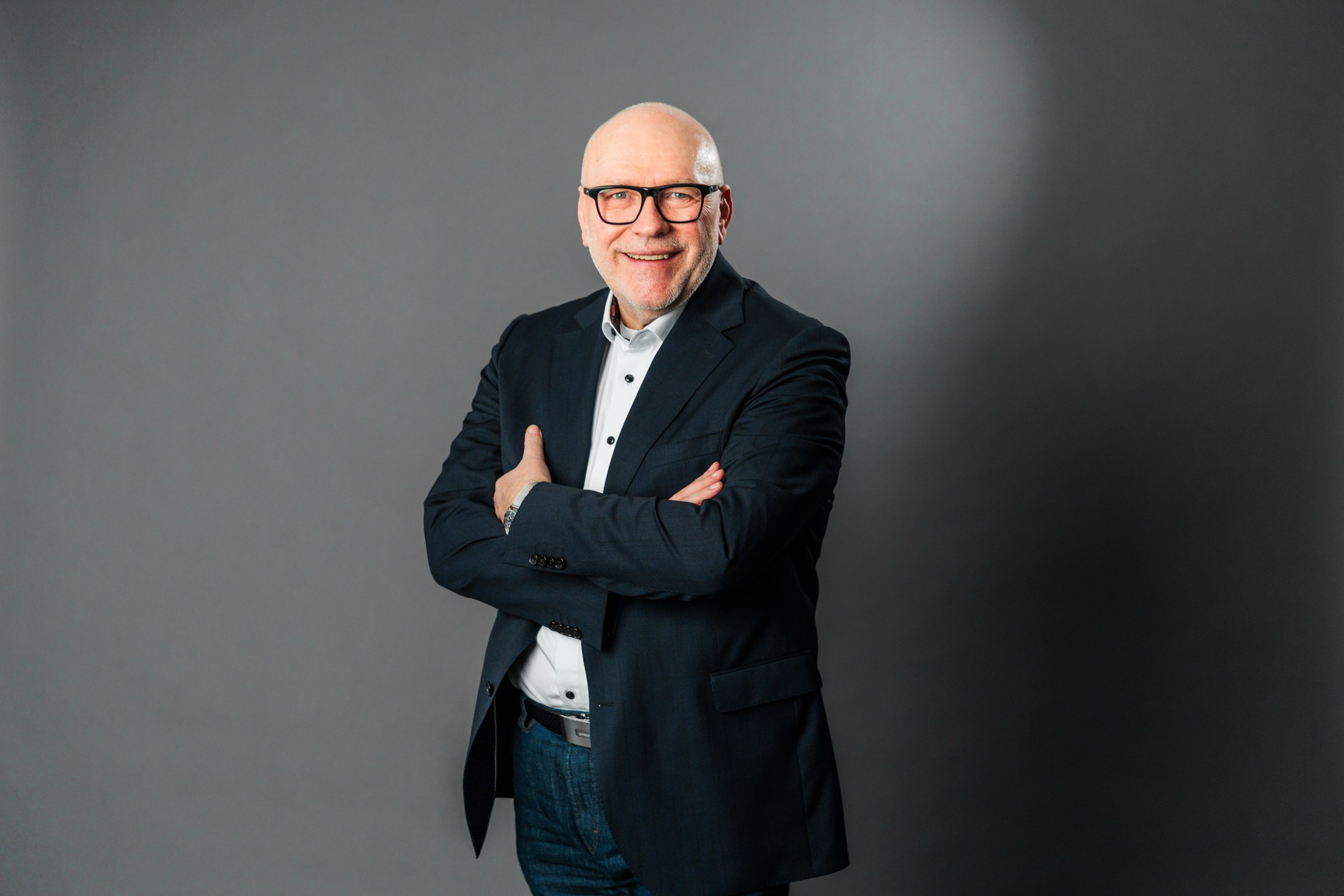 Jürgen Engelberth, entspannt mit verschränkten Armen im dunklen Anzug